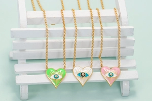 Detailed macro of colorful heart evil eye pendants on gold chains in bohemian style