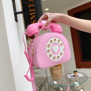 Detail of creative pink telephone handbag featuring vintage dial and gold hardware accents