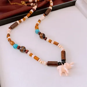 Collana etnica con perle di legno, pietre turchesi e un ciondolo a forma di elefante rosa