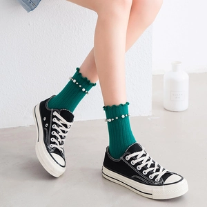 Green mid-tube socks with elegant pearl accents and ruffled edges on model