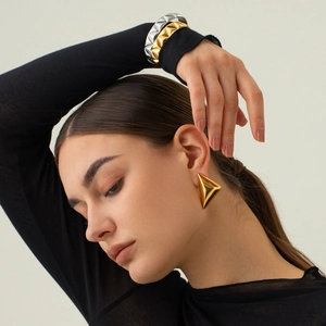 Orecchini a rombo in oro 18k e braccialetti geometrici indossati da una modella