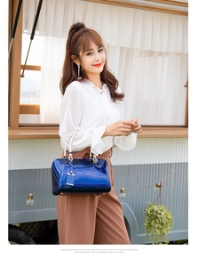 Outdoor shot of royal blue patent leather Boston handbag with textured handles