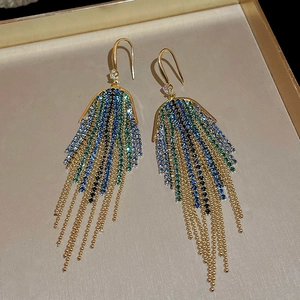 Close-up of golden tassel earrings with gradient blue and green crystals and rhinestones