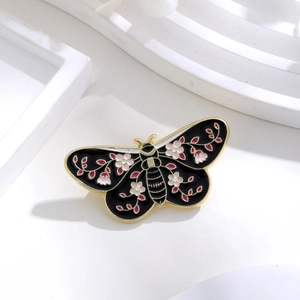 Detailed close-up of a black enamel butterfly brooch with pink cherry blossom patterns