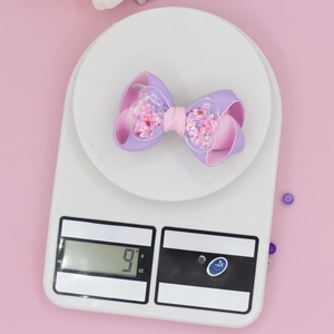 Detailed view of 9g purple and pink grosgrain bow hair clip with sequined hearts