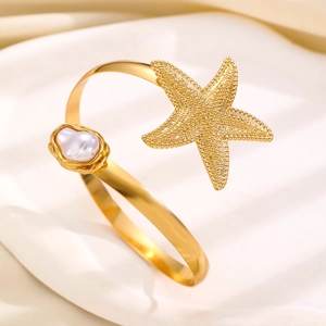 Ocean style gold starfish upper arm cuff with white baroque pearl on textured pedestal