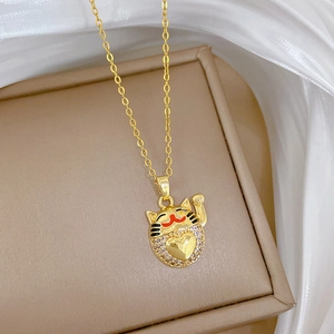 Close-up of golden Maneki-neko necklace pendant with zircon heart on silk background