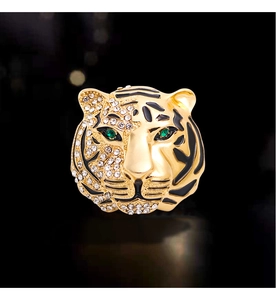 Close-up of gold tiger brooch with white rhinestones, black enamel, and green gem eyes