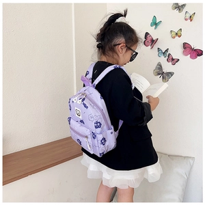 Bimbo indossa uno zainetto viola con gufi colorati mentre legge un bel libro