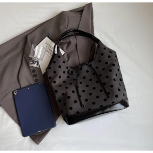 Detail of grey canvas tote bag with black polka dots on a stylish blazer background