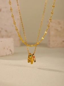 Macro view of gold triple-ring pendant with colored zircons and 'with love' engraving