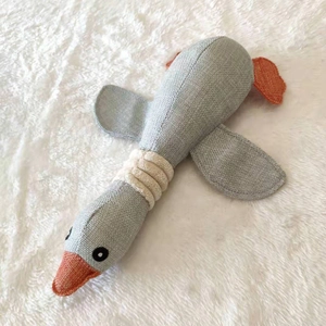 Gray goose plush squeaky dog toy with linen texture and orange feet on white fur rug