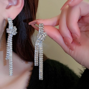 Elegant silver knotted tassel earrings with zircon crystals shown on a model's ear