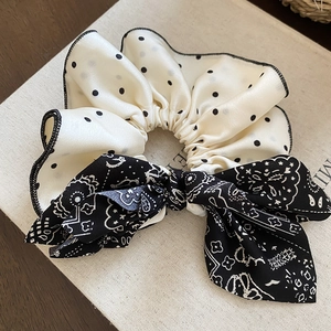 Vue détaillée du chouchou en tissu à pois et motif cachemire avec un grand nœud