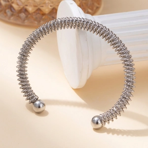 Detailed shot of silver elastic steel wire cuff bracelet with metal spring texture and beads