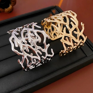 Luxe hollow coral branch open bangle in gold and silver finish on jewelry tray