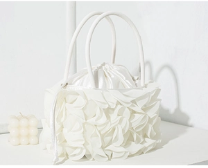 Detail view of the white floral evening bag with layered petals and round handle