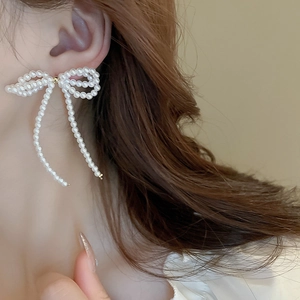Elegant bow knot tassel earrings with white imitation pearls on model