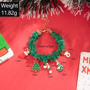 Green beaded Christmas bracelet with festive enamel charms on a red background