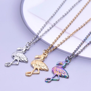 Three flamingo pendant necklaces in silver gold and rainbow plating on a soft purple display