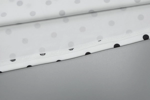 Macro shot of polka dot print fabric and detailed edge stitching on a summer dress