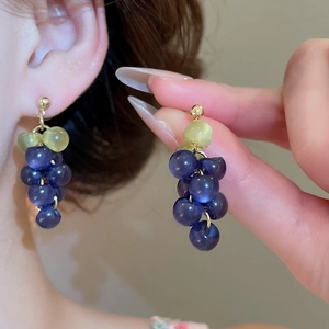 Macro view of purple resin grape earrings with gold needle tassels and leaf detail