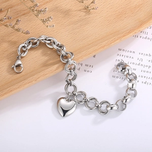 Macro detail of silver-tone chunky chain link bracelet with heart pendant and lobster clasp