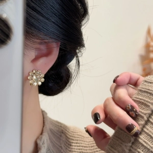 Detailed close-up showing a sparkling crystal flower earring on a model's ear