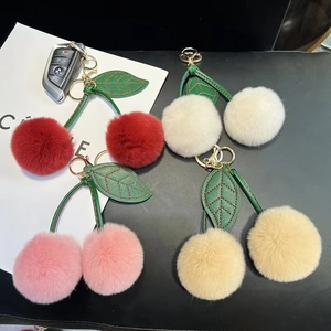 Detail of plush cherry keychains in four colors with soft fur and leather leaves