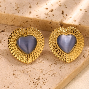 Macro shot of vintage heart stud earrings with blue gemstone and gold bead texture