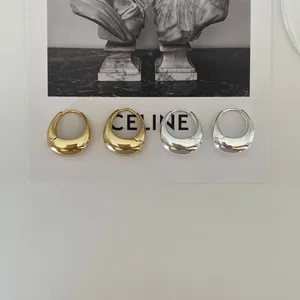 Close-up of minimalist gold and silver teardrop hoop earrings with polished finish
