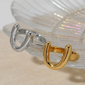Minimalist U-shaped stainless steel rings in gold and silver on an iridescent shell tray