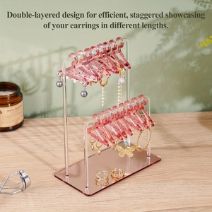 Detail view of pink acrylic earring stand with mini clothes hangers and a mirrored base