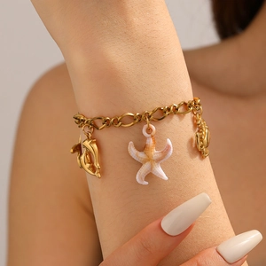 Dettaglio di un bracciale dorato con ciondoli a forma di stella marina, delfino e granchio
