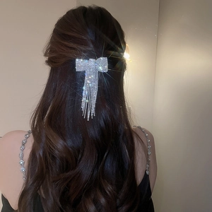 Barrette à nœud strass étincelante avec pompons portée sur cheveux longs