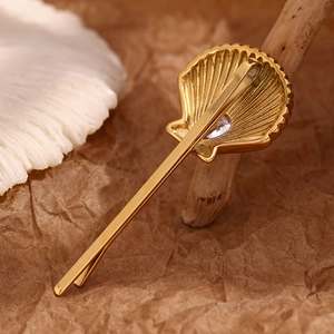 Close-up of a 18K gold plated stainless steel seashell hair clip with a sparkling zircon