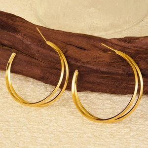 Macro detail of high-polish double layer gold stainless steel hoop earrings on wood