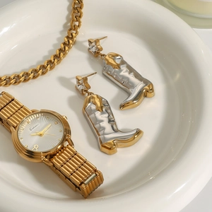 Star-studded gold and silver cowboy boot dangle earrings on a luxury ceramic tray