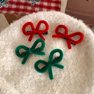 Christmas bow hair clips set with red and green fuzzy pipe cleaners on white wool background