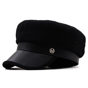 Detail view of black octagonal newsboy hat showing knit crown and PU leather brim