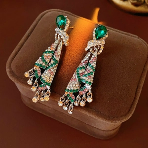 Close-up of vintage emerald and pink rhinestone tassel earrings on a brown velvet box