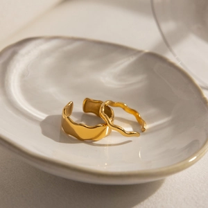 Detailed view of two gold stainless steel rings with minimalist wavy lava textures