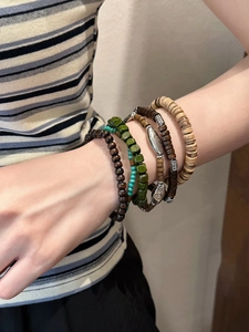 Gros plan de bracelets en perles de bois bohèmes avec des breloques ethniques sur un poignet