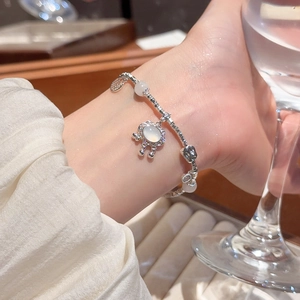 Detail of silver chain bracelet featuring a unique oval moonstone lock charm on wrist