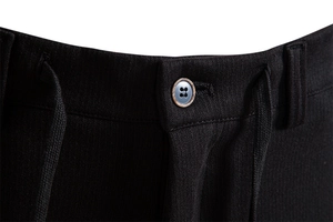 Detail of men's casual pants featuring a wooden texture button and ribbed fabric weave