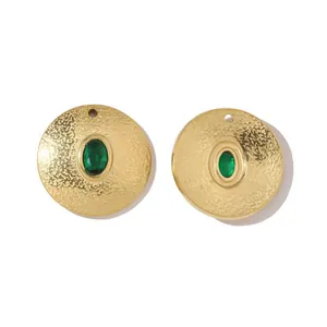 Detail eines goldfarbenen Ohrrings mit Hammerschlag-Textur und grünem Edelstein-Inlay