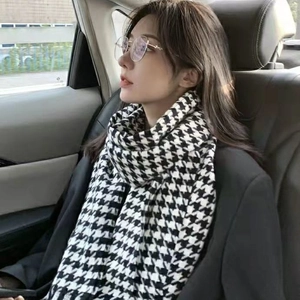Detail shot of a black and white houndstooth scarf worn by a model in a car setting