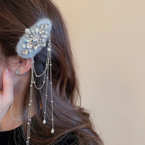 Detail of grey flocked bow hair clip with crystal clusters, silver tassels, and pearl drops