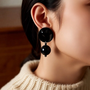 Detail of a chic black acrylic double-ball dangle earring worn on model for fashion display