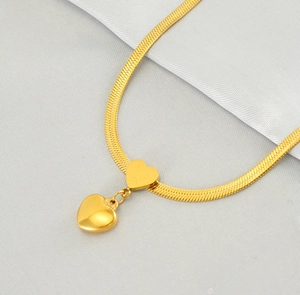 Macro detail of gold snake chain with flat heart and puffed heart pendant jewelry